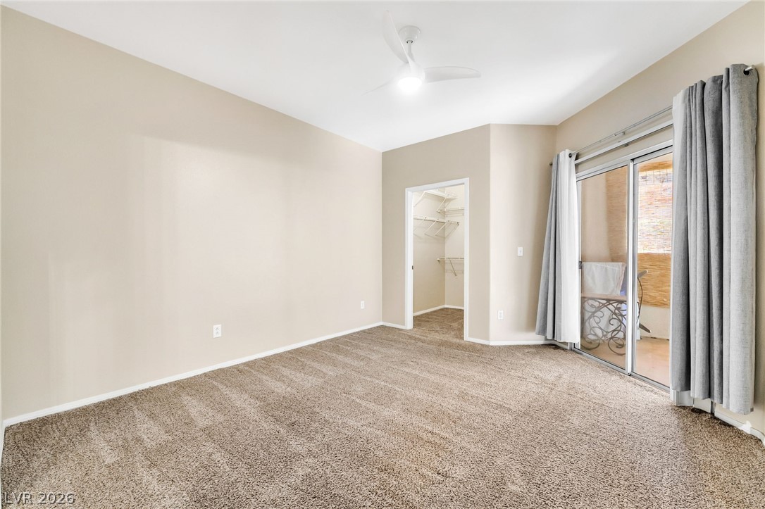 2050 West Warm Springs Road, Unit 2411 Henderson, NV 89014 - Photo 16 of 37 A well-lit bedroom with plush carpeting, a walk-in closet, and direct balcony access.