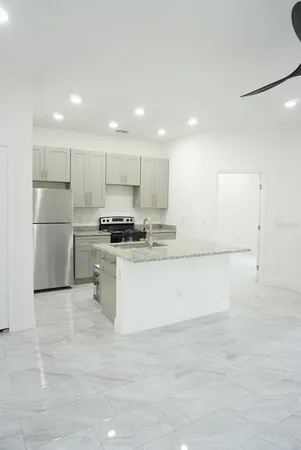 a kitchen with stainless steel appliances granite countertop a refrigerator sink and white cabinets