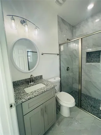 a bathroom with a granite countertop sink toilet a mirror and shower