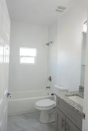 a bathroom with a granite countertop toilet a sink and bathtub