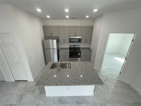 a kitchen with kitchen island a counter top space a sink and a refrigerator