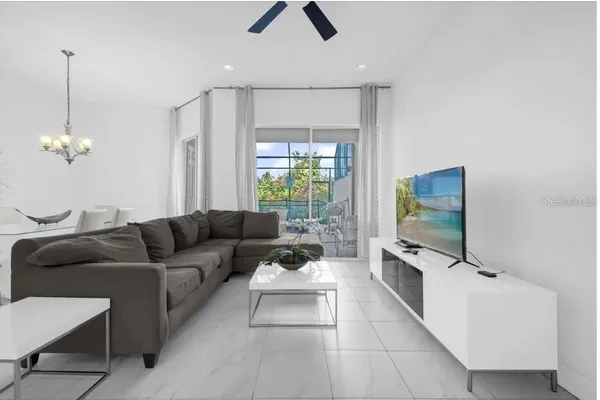 a living room with furniture a flat screen tv and a chandelier