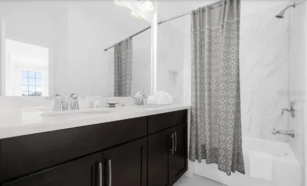 a bathroom with a double vanity sink a mirror and a bathtub