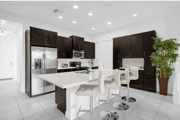 a kitchen with stainless steel appliances kitchen island granite countertop a refrigerator and a stove top oven