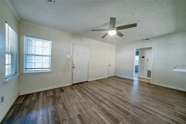 an empty room with wooden floor ceiling fan and windows
