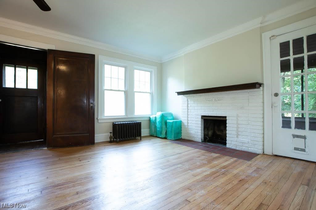 1106 Hillstone Road Cleveland Heights, OH 44121 - Photo 4 of 35 Hardwood floored living room featuring a fireplace, brick wall, ornamental molding, and radiator heating unit