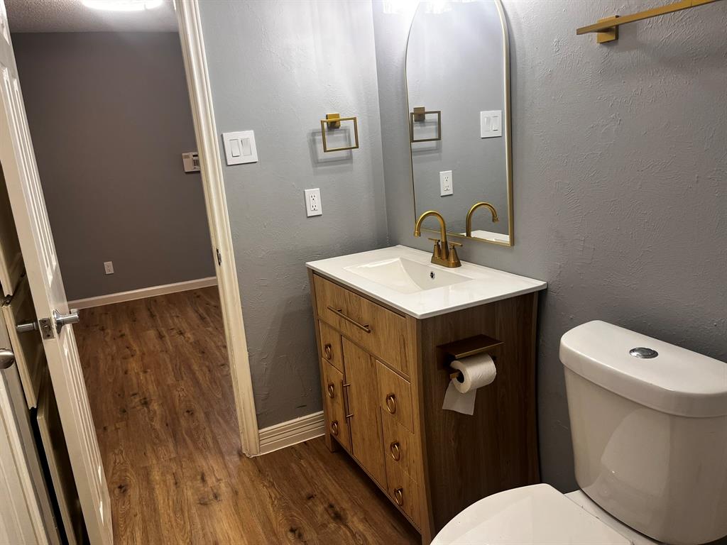 1007 Mack Place Denton, TX 76209 - Photo 20 of 37 Half bathroom featuring vanity, a textured wall, and dark wood-type flooring