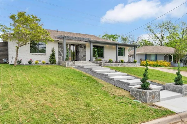 a front view of a house with garden and trees