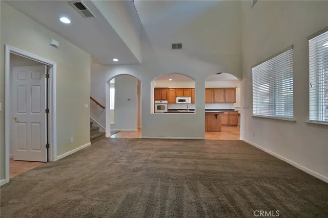 an empty room with a chandelier fan and windows