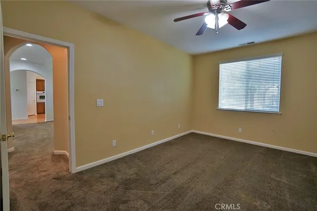 an empty room with chandelier fan and windows