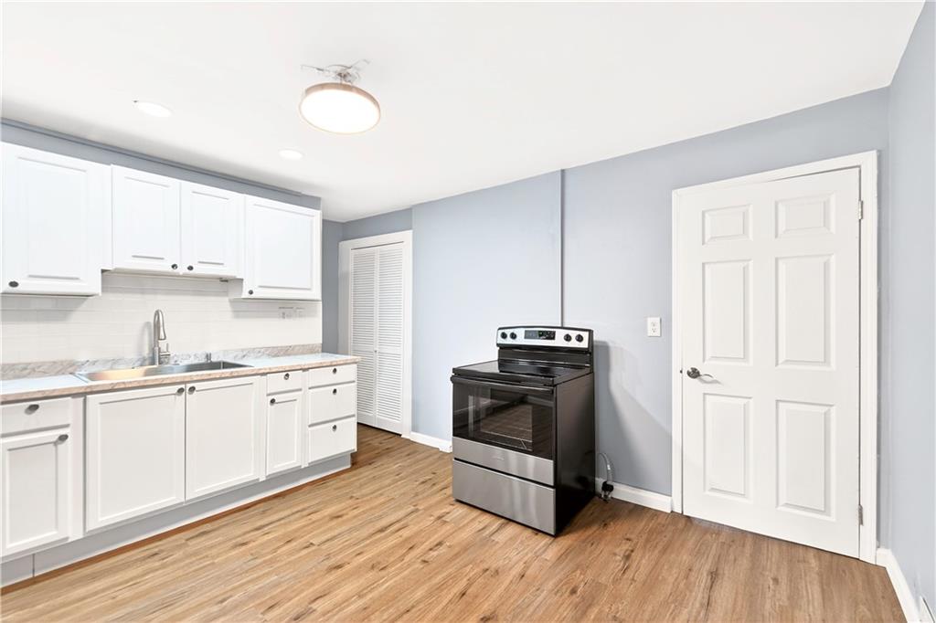 93 Old 51 Road Perryopolis, PA 15473 - Photo 11 of 44 a kitchen with stainless steel appliances a stove a sink and white cabinets with wooden floor