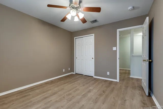 an empty room with closet and a chandelier fan