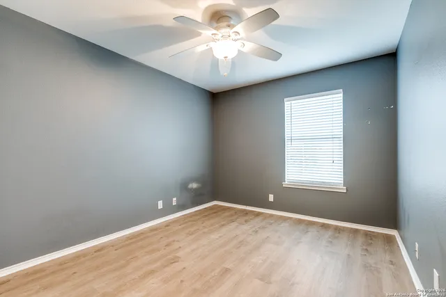 an empty room with a chandelier fan and windows