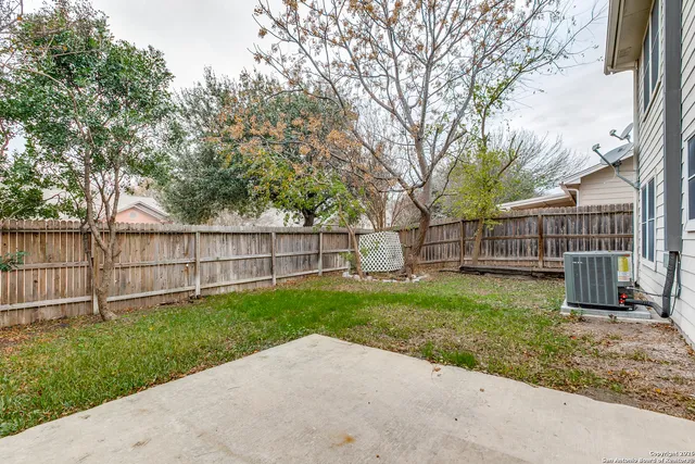 a view of a backyard with wooden fence and large trees