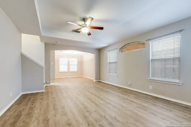 a view of an empty room with chandelier fan and a fireplace