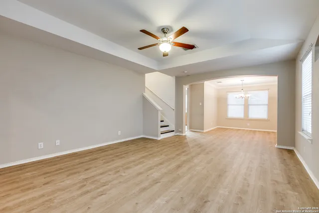 a view of an empty room with wooden floor and a ceiling fan