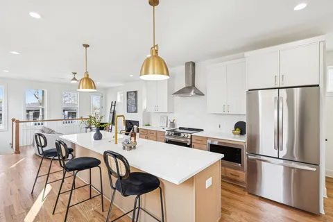 a kitchen with stainless steel appliances a dining table chairs stove and refrigerator