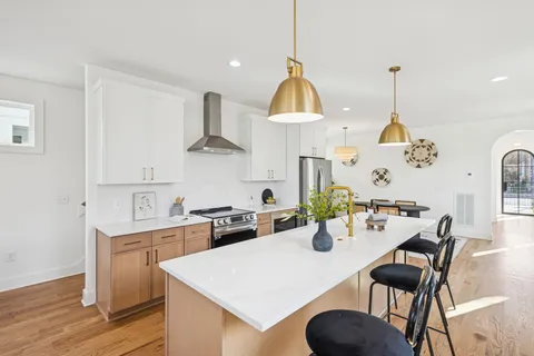 a kitchen with stainless steel appliances a dining table chairs and white cabinets