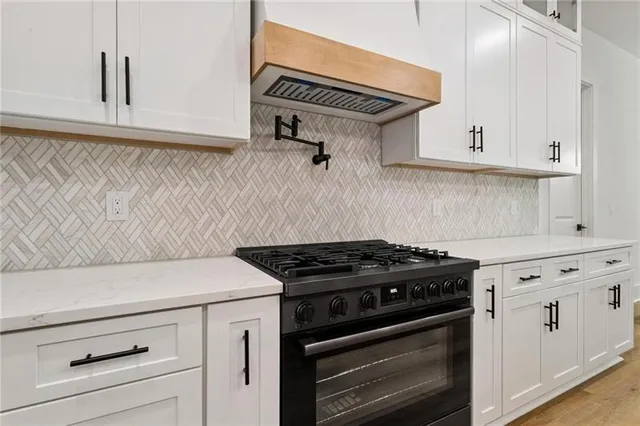 a kitchen with stainless steel appliances granite countertop a sink a stove and a wooden floors