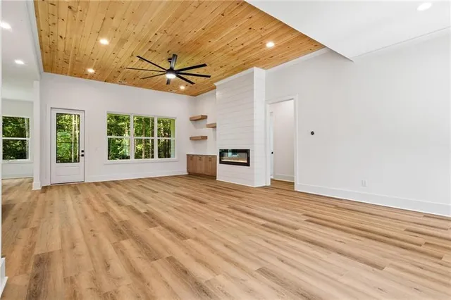 a view of empty room with wooden floor and fan