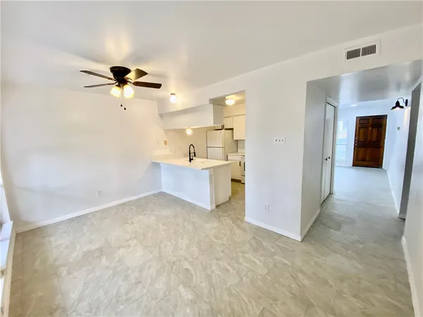 a view of a room with a ceiling fan and refrigerator