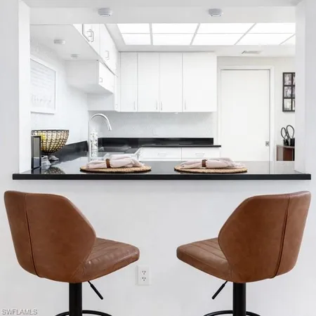 a kitchen with granite countertop a sink and white cabinets