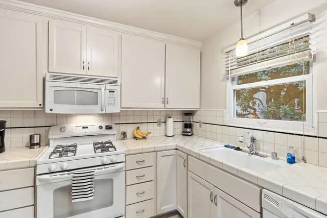 a kitchen with cabinets appliances a sink and a window