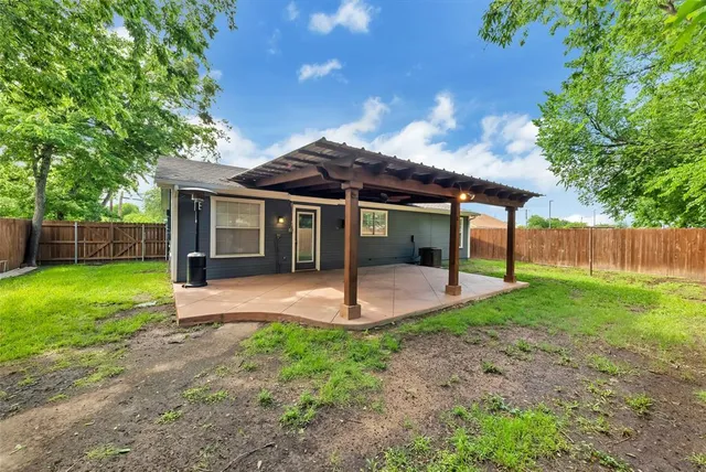 a view of a backyard with a barbeque grill and a large tree