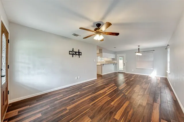 a view of empty room with wooden floor and fan
