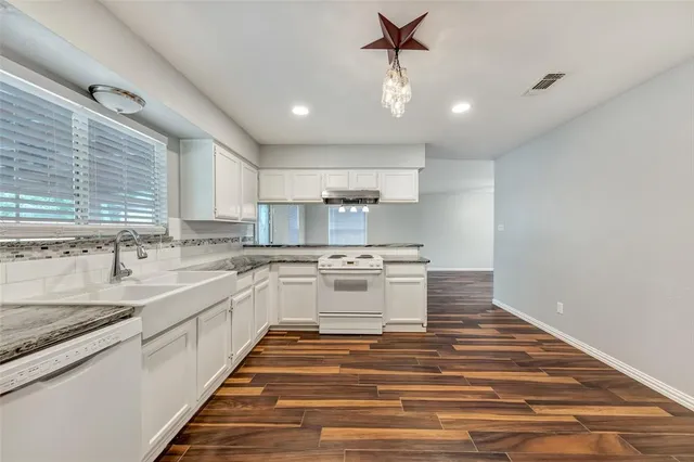 a large white kitchen with kitchen island a sink stainless steel appliances and window