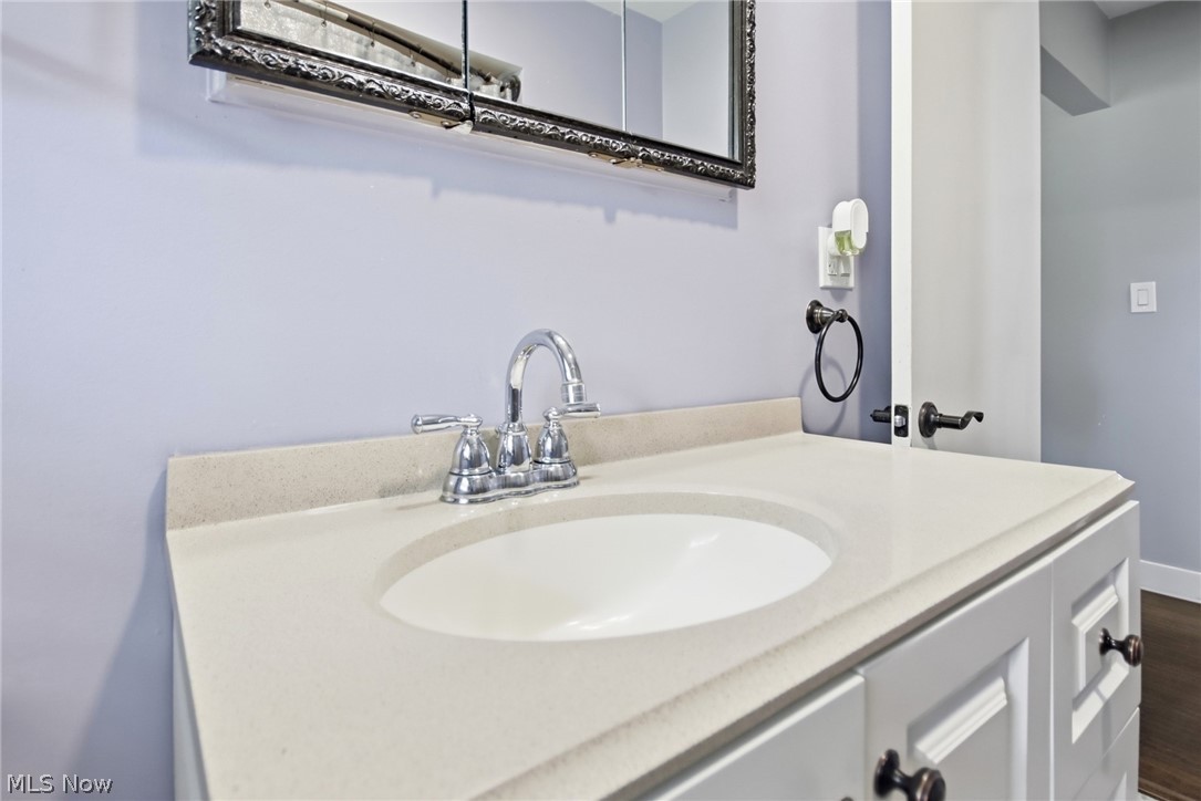 12684 Taylor Wells Road Chardon, OH 44024 - Photo 23 of 40 White vanity with bronze hardware, a light-toned countertop, and an integrated white sink with a polished chrome faucet