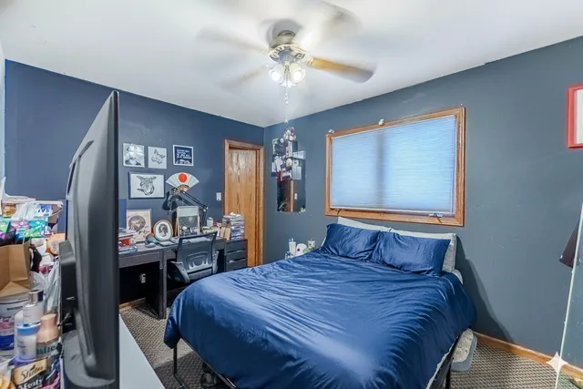 a bedroom with a bed and dresser with wooden floor