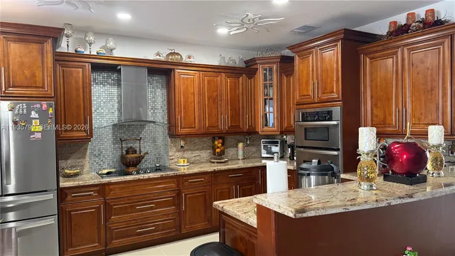 a kitchen with stainless steel appliances granite countertop a sink refrigerator and cabinets