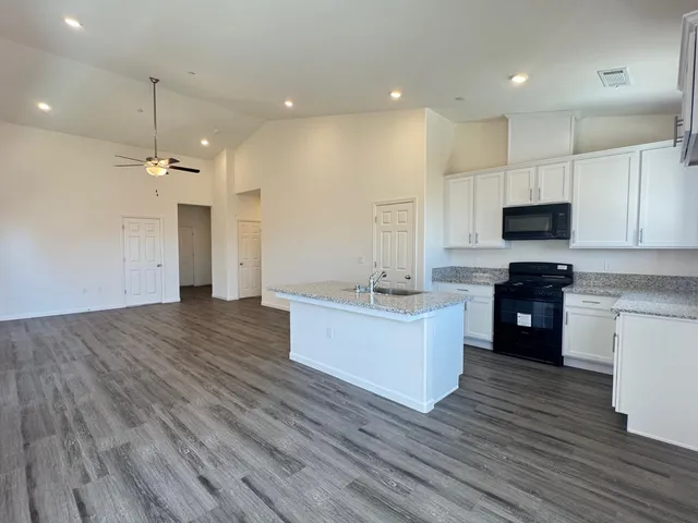 a large kitchen with kitchen island a stove a sink dishwasher and a oven with wooden floor