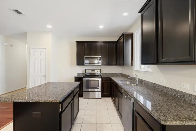 a kitchen with stainless steel appliances granite countertop granite counter tops a stove a sink and a refrigerator