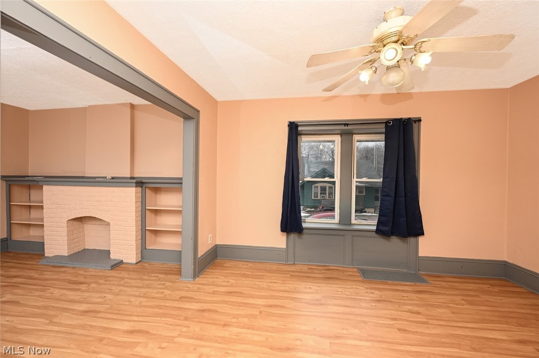 77 West Mildred Avenue Akron, OH 44310 - Photo 12 of 40 Unfurnished living room featuring a ceiling fan, light wood-style flooring, and a brick fireplace