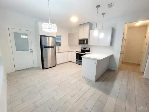 a large kitchen with stainless steel appliances a refrigerator a stove a sink and a refrigerator