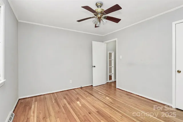 an empty room with a ceiling fan and wooden floor