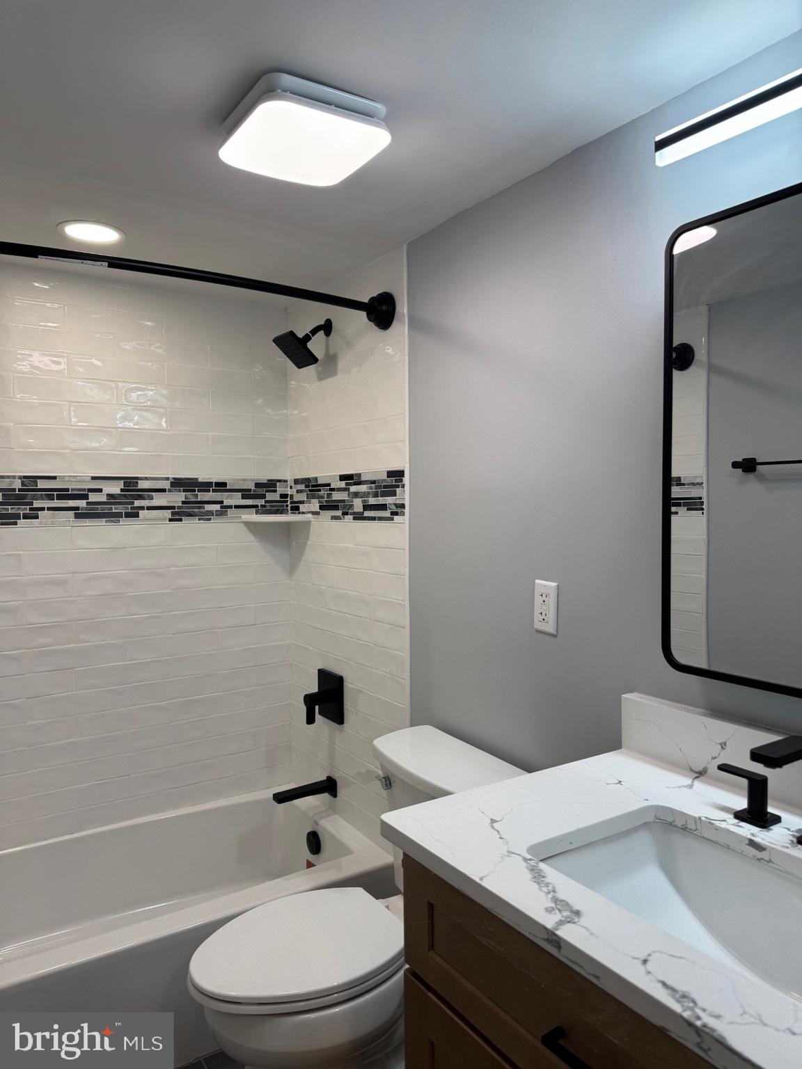 317 Homeland Southway, Unit 2A Baltimore, MD 21212 - Photo 8 of 16 a bathroom with a granite countertop sink toilet a mirror and shower