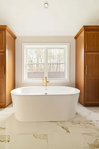 a white bath tub sitting in a bathroom next to a window
