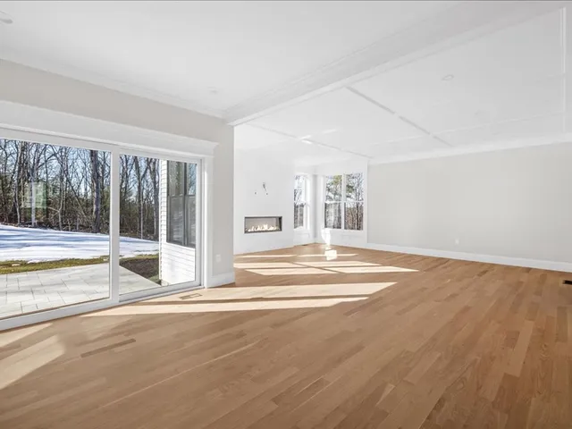 a view of an empty room with wooden floor and a fireplace