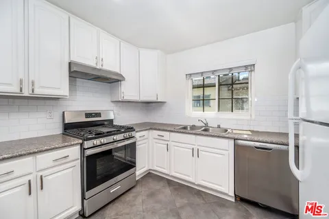 a kitchen with granite countertop white cabinets and stainless steel appliances