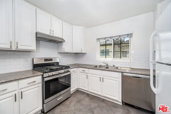 a kitchen with granite countertop white cabinets and stainless steel appliances