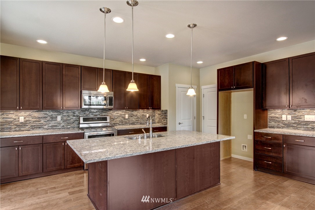 3530 178th Place Southeast, Unit 3013 Bothell, WA 98012 - Photo 4 of 11 a kitchen with stainless steel appliances kitchen island granite countertop a stove a sink and a refrigerator