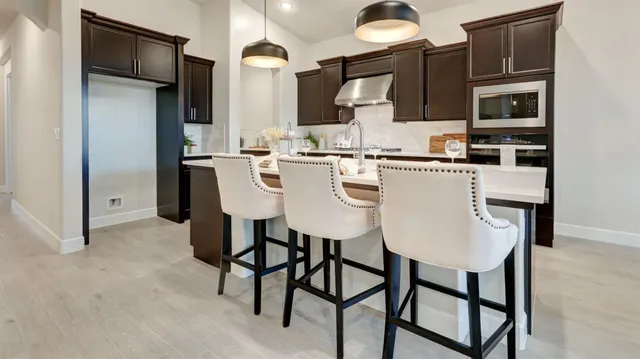 a kitchen with stainless steel appliances kitchen island granite countertop a refrigerator and microwave