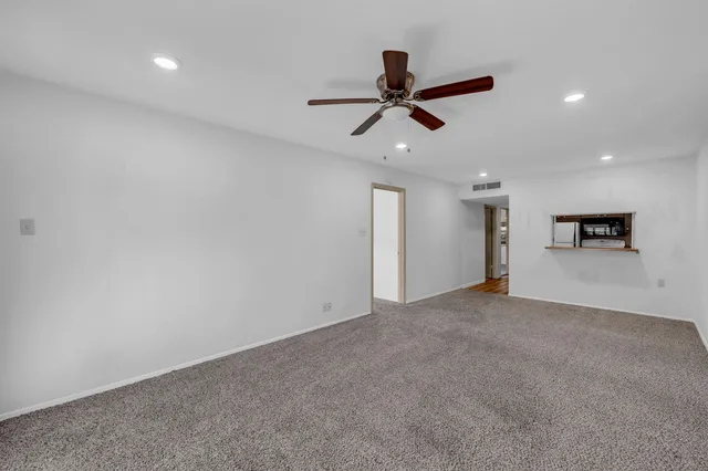 an empty room with a kitchen space and stainless steel appliances