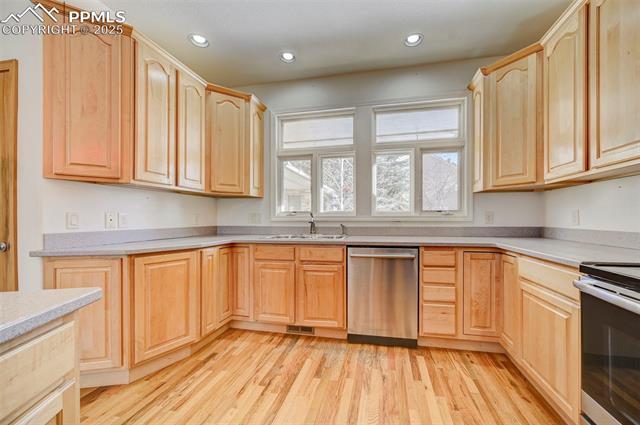 15091 Ridgefield Lane Colorado Springs, CO 80921 - Photo 16 of 35 Kitchen featuring appliances with stainless steel finishes, light brown cabinetry, sink, and light wood-type flooring