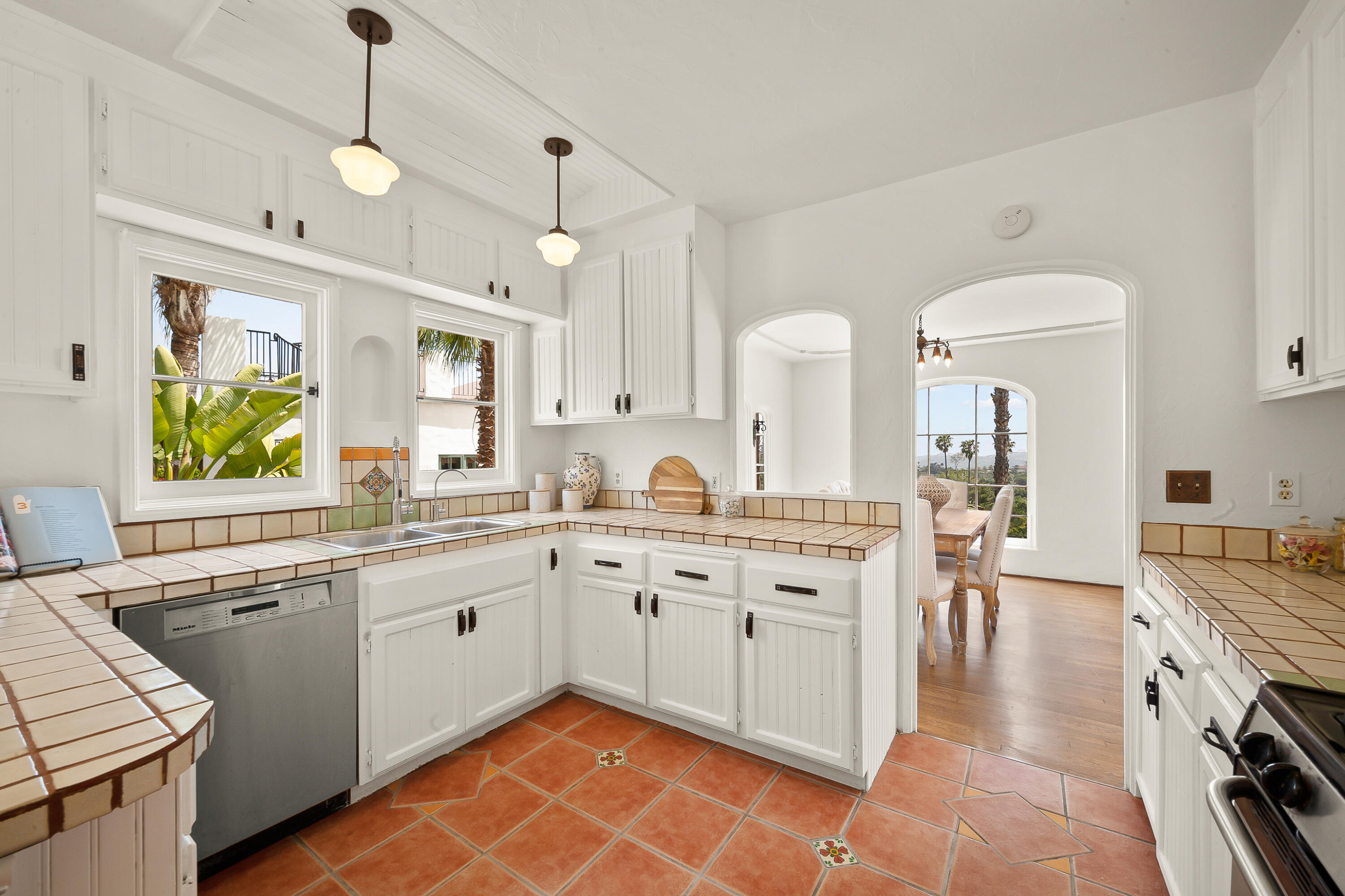 870 Windsor Way Santa Barbara, CA 93105 - Photo 8 of 59 a large white kitchen with a stove top oven a sink a dining table and chairs with wooden floor