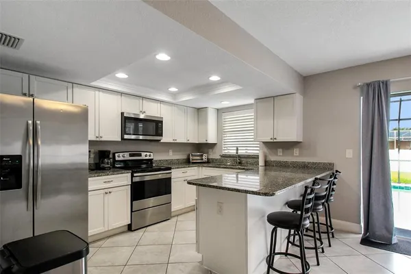 a kitchen with stainless steel appliances granite countertop a stove a sink a refrigerator a microwave a counter and cabinets