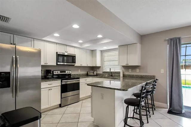 a kitchen with stainless steel appliances granite countertop a stove a sink a refrigerator a microwave a counter and cabinets